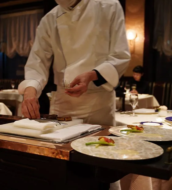 ワゴンで肉料理を切り分けるシェフ